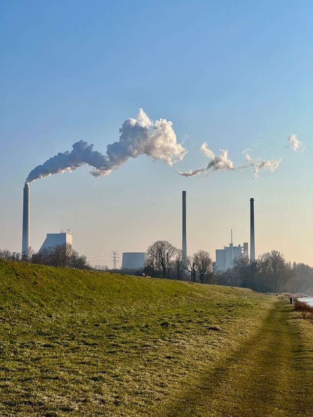 Industrial chimneys with smoke emissions under a clear blue sky